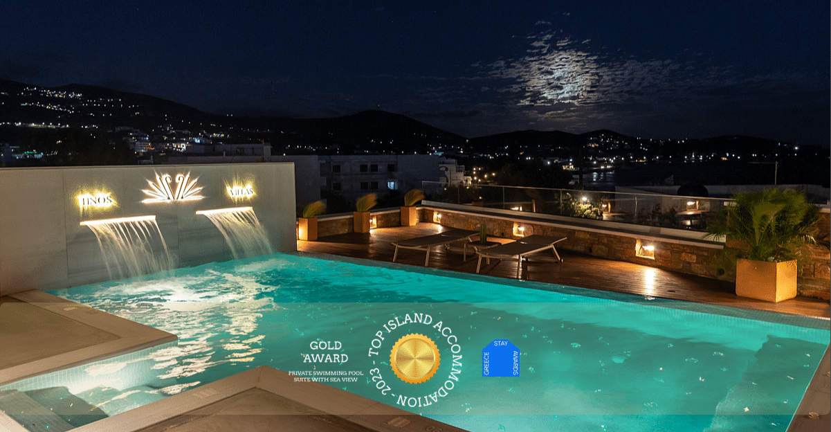Dreamy photo of a private swimming pool at night, with fullmoon and atmospheric lighting, of a luxury villa in Tinos, looking at the sea, with a gold award logo "Top Island Accommodation 2023 - Greece Stay Awards"